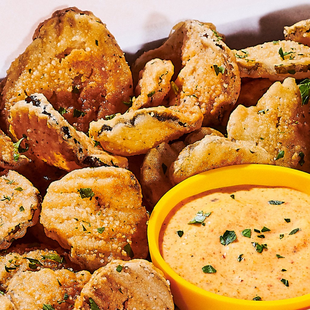 close up of fried pickles and sauce in bowl