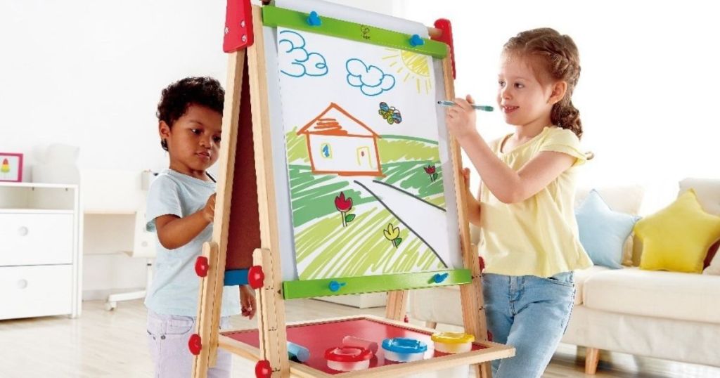 two kids drawing on an art easel