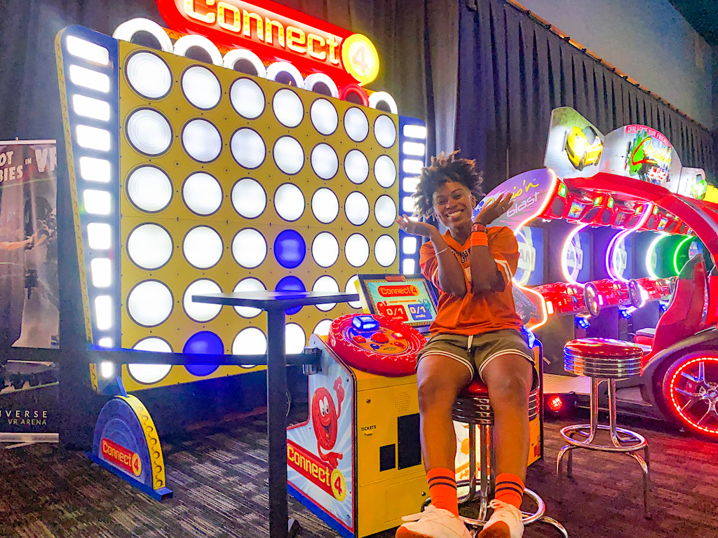 person sitting by Connect 4 game at Dave & Busters 