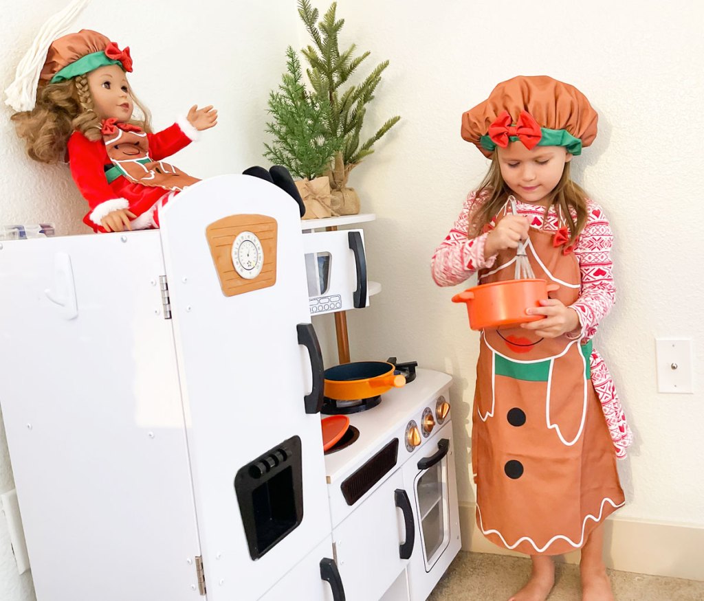 girl in gingerbread apron in play kitchen