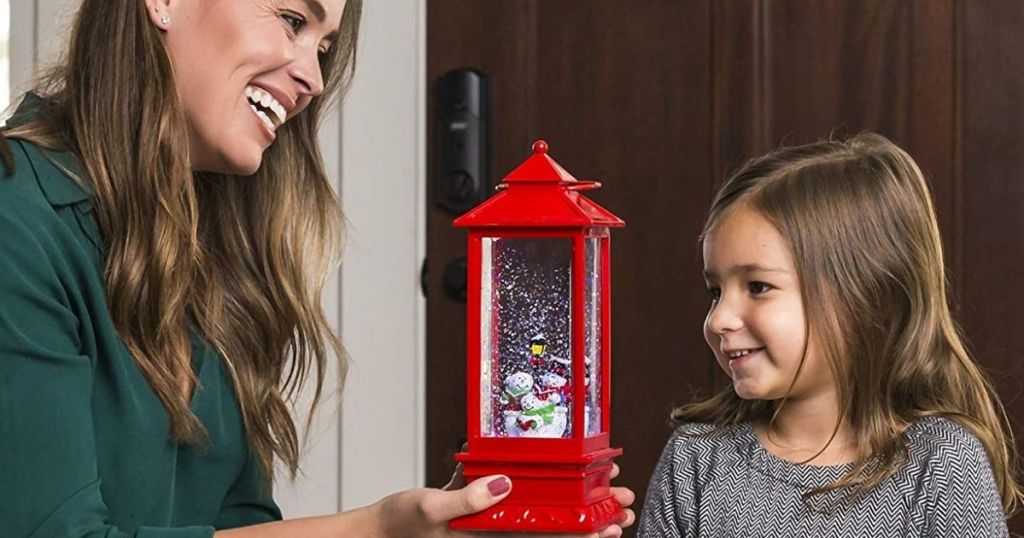 woman holding a snow globe next to a little girl