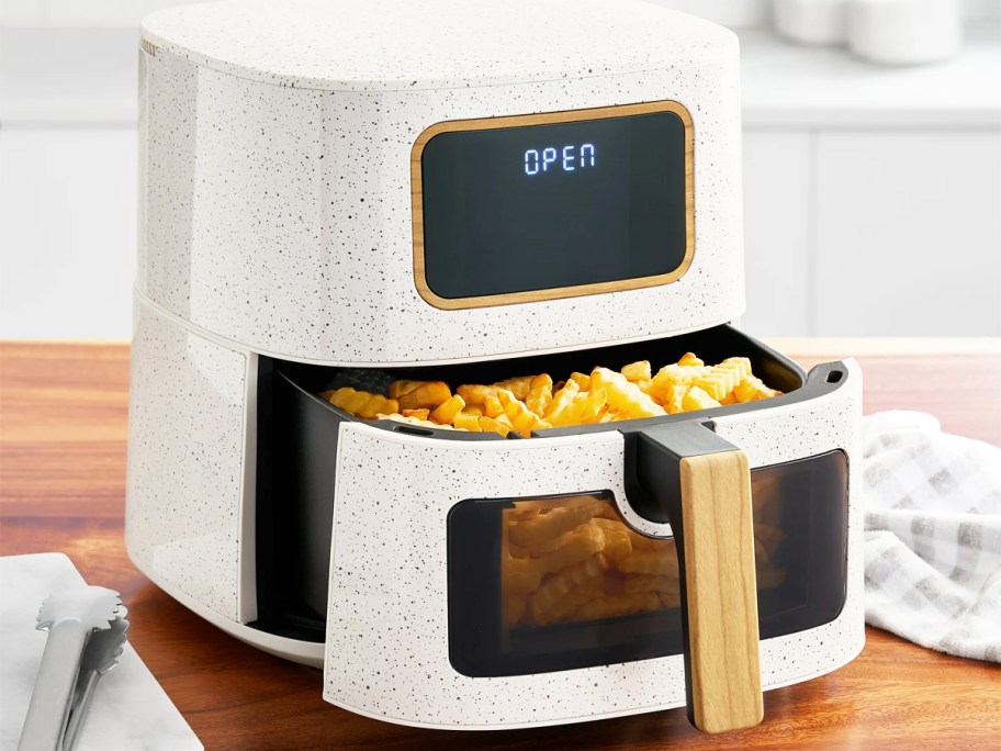 white speckled air fryer on counter with basket full of fries