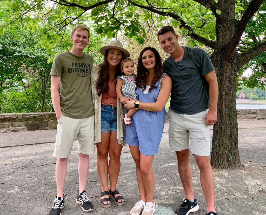 family holding baby girl and standing outside in woods