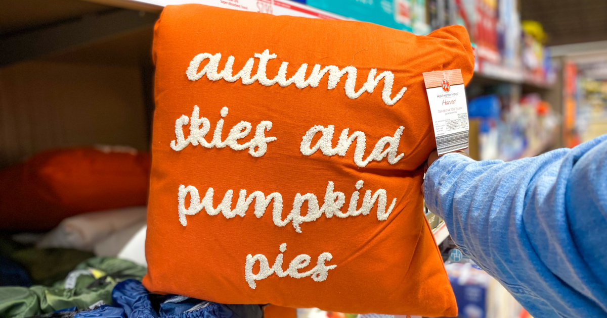 hand holding up orange throw pillow in store