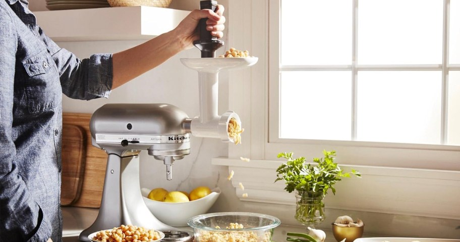 hand using kitchenaid food grinder with meat pouring into bowl 