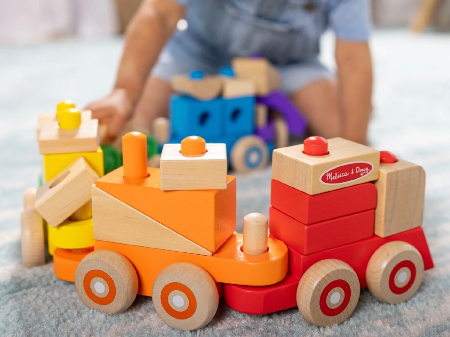 boy playing with wooden melissa doug train set