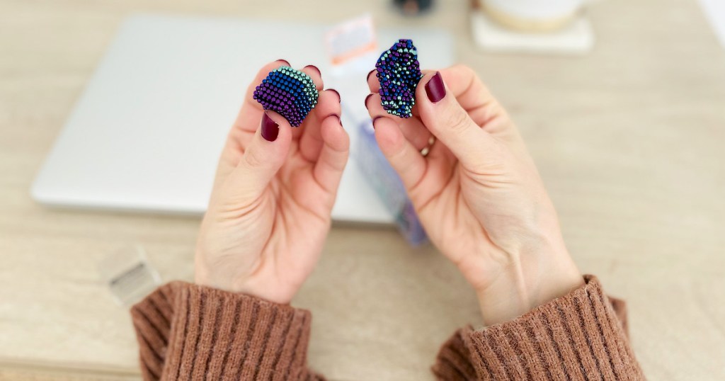 hands holding colorful magentic balls over desk