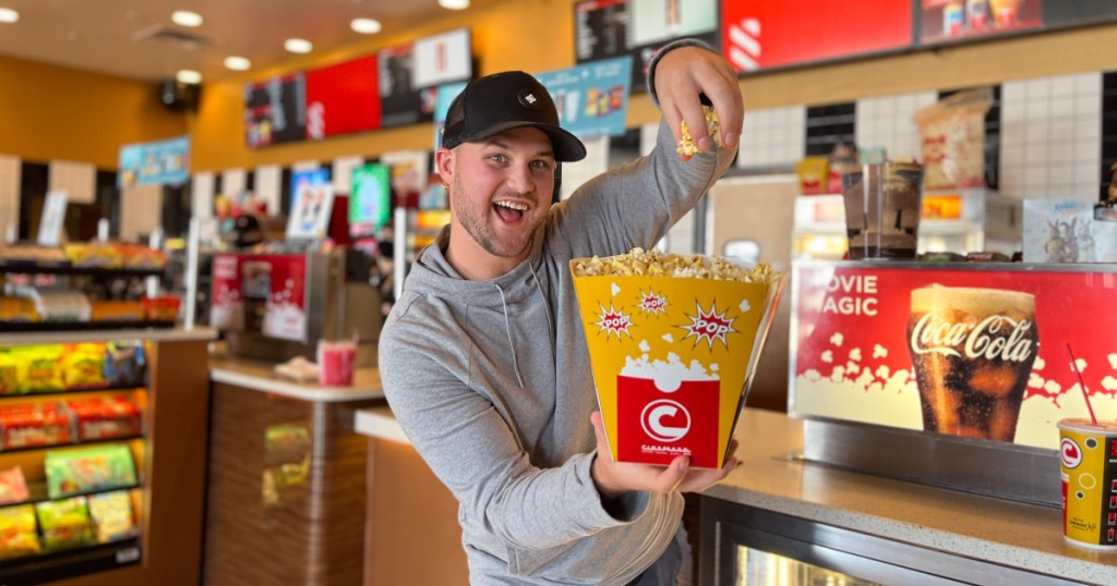 man holding a bag of popcorn in a movie theater