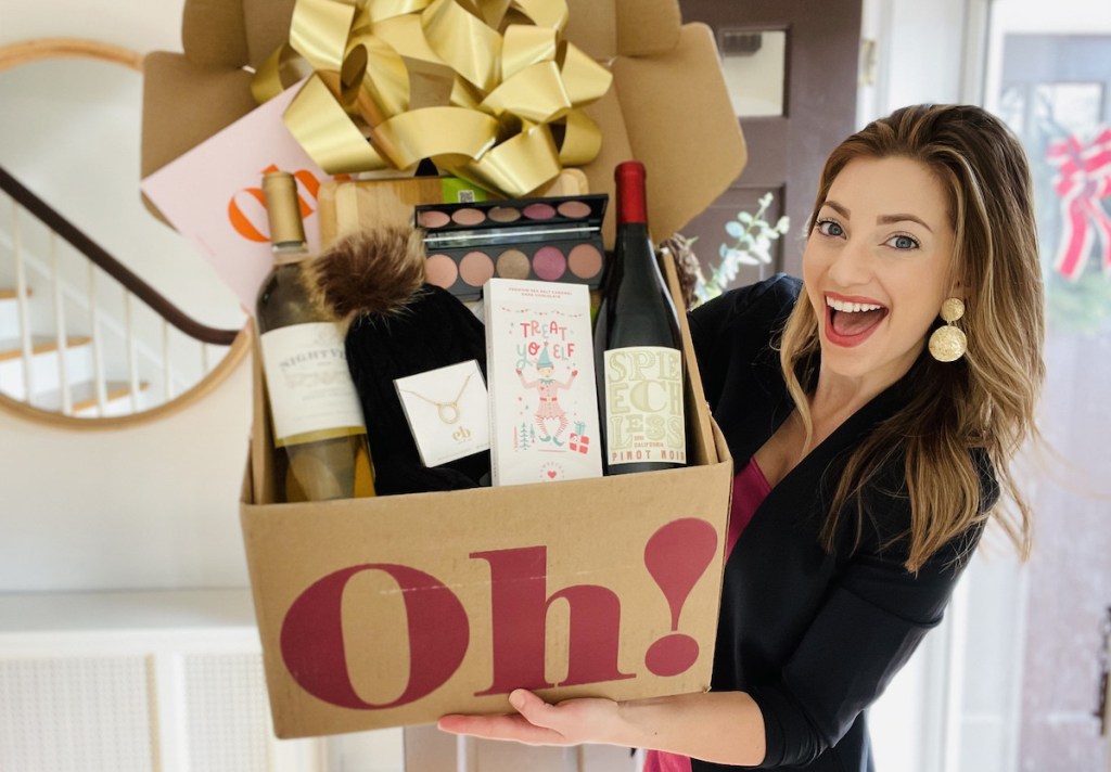 woman holding up box full of goodies by front door