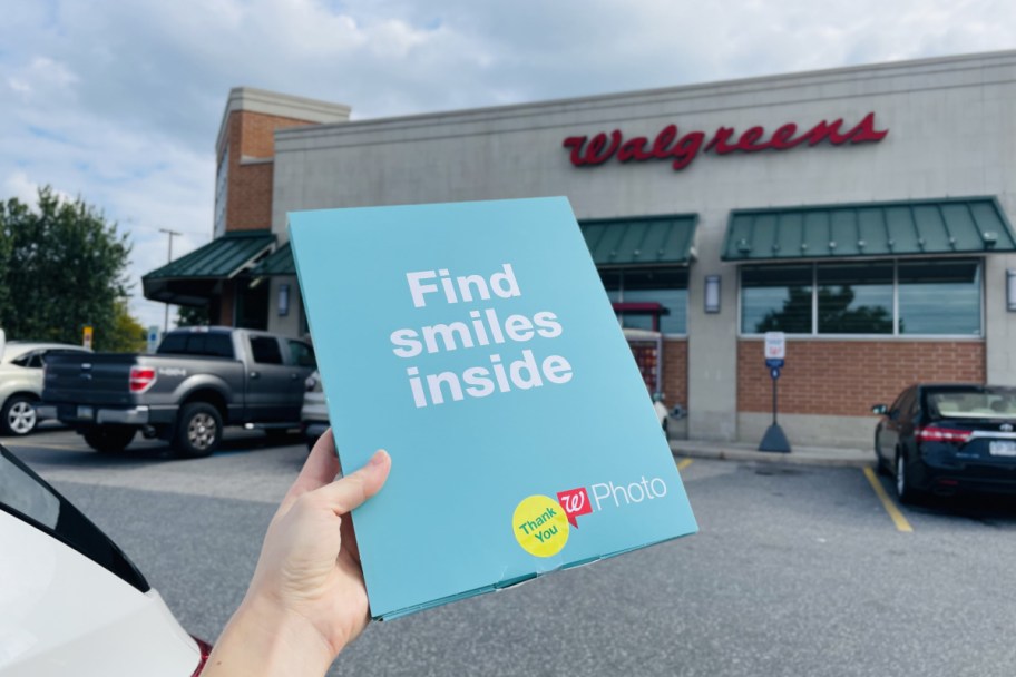 holding a blue photo folder outside of Walgreens