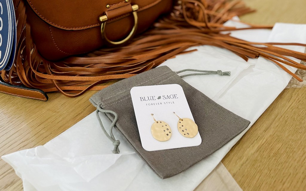 gold disc earrings on table with canvas bag