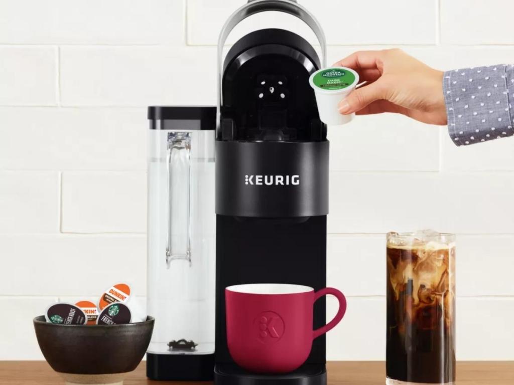 hand holding kcup putting into keurig k-supreme coffee maker