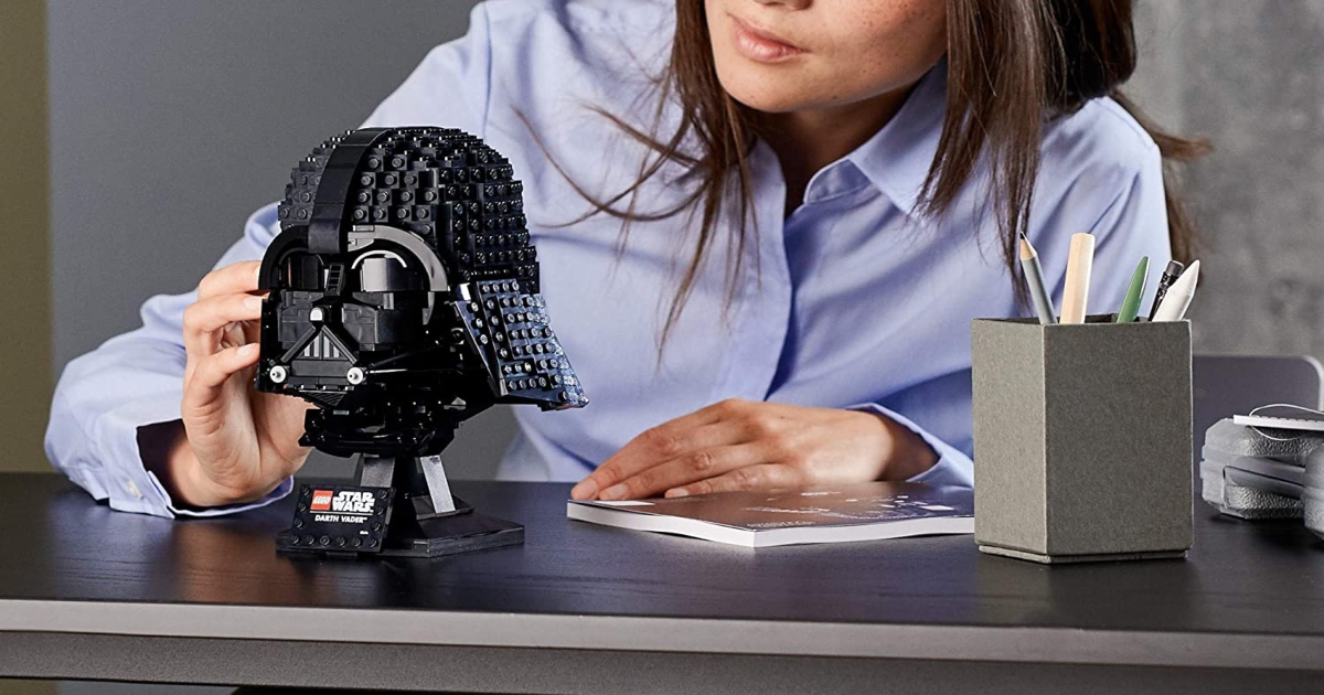 A woman at a desk putting together the black Lego Star Wars Helmet