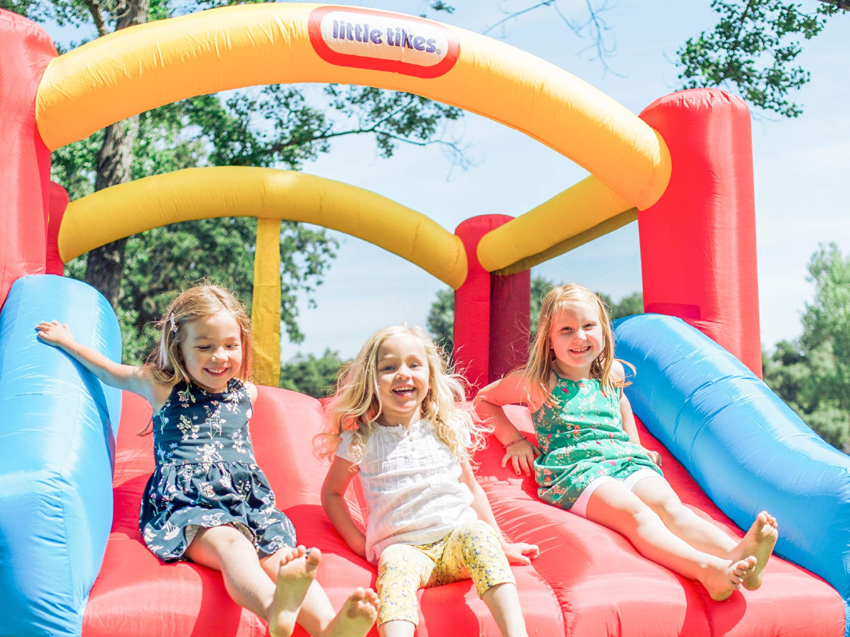 three girls onlineing down slide in inflatable bounce house