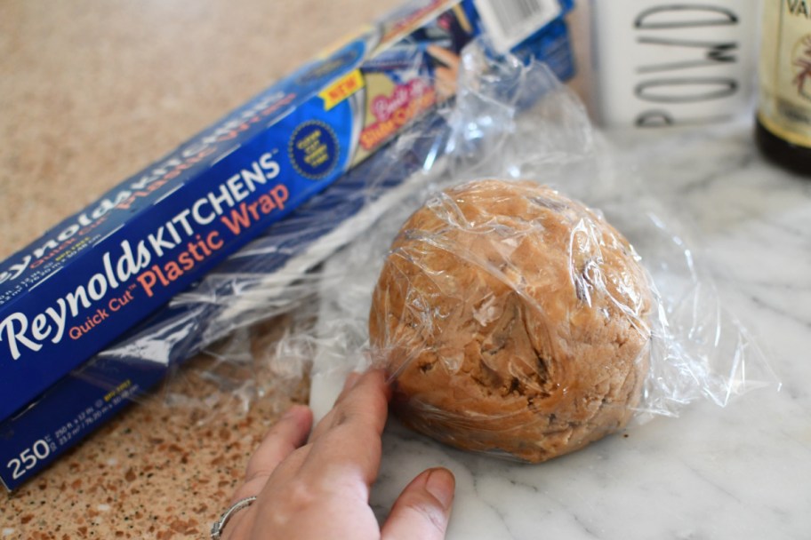 Making a Reese's Peanut Butter Ball by wrapping it in plastic wrap