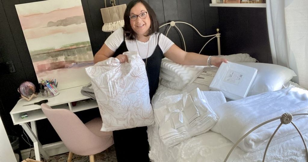 woman holding up OCM bedding and bath products