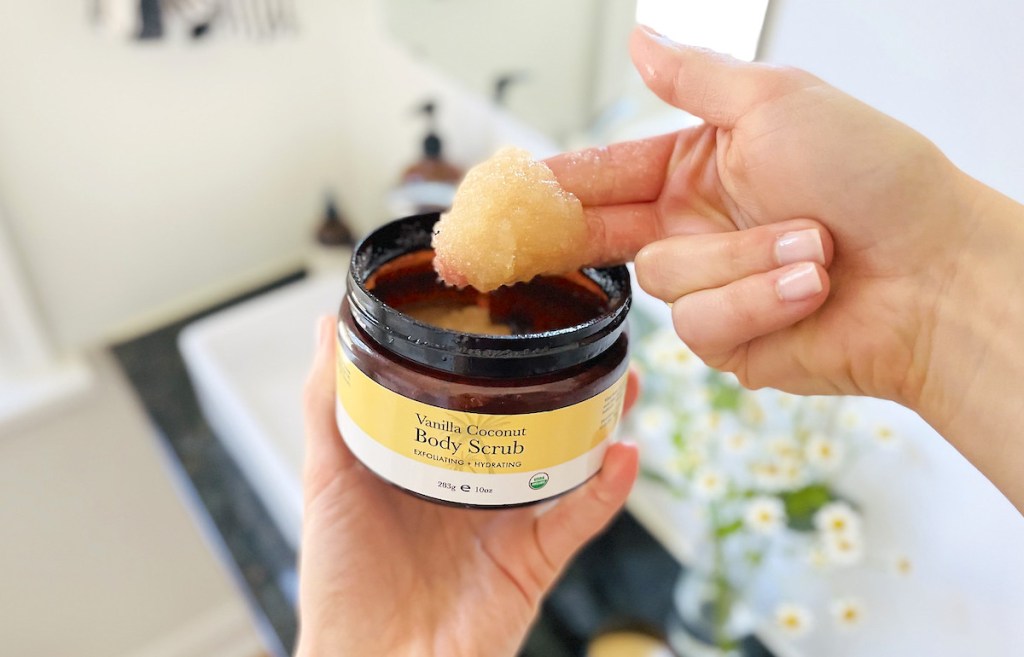 close up of fingers dipping into beauty by earth vanilla coconut body scrub 