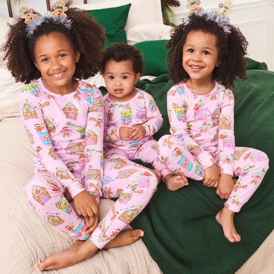 3 little girls wearing matching pink christmas pajamas