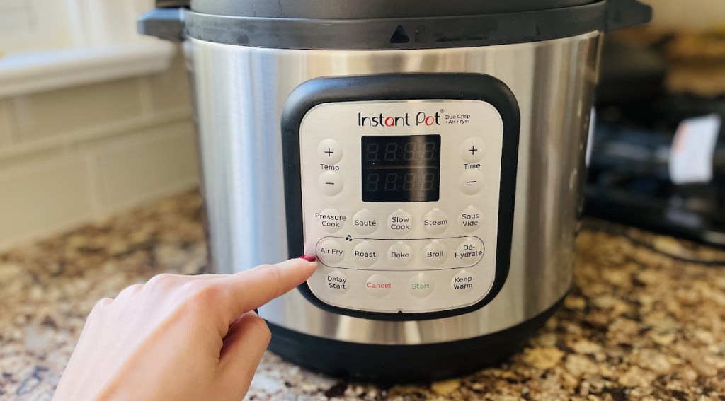 finger pressing on control panel on kitchen appliance