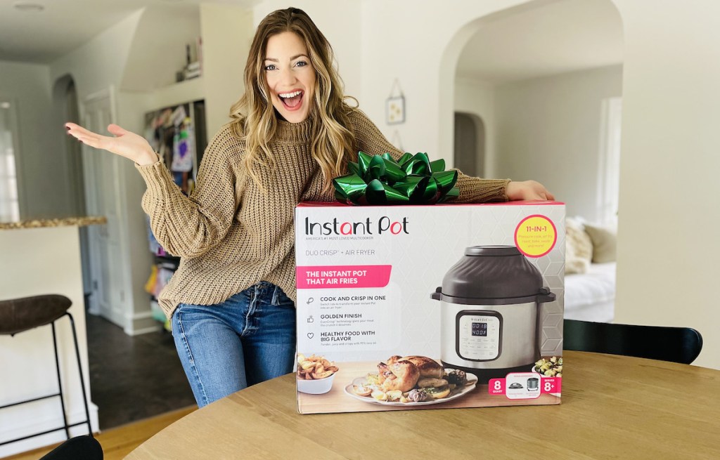 woman standing next to box with big green christmas bow on top