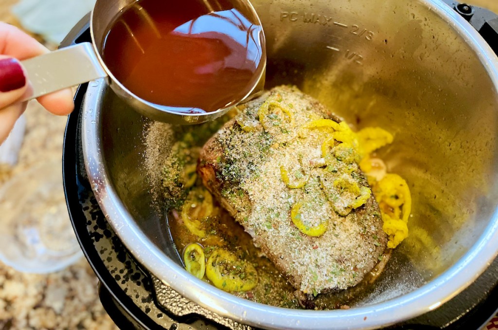 hand holding stainless steel measuring cup with beef broth pouring into pot