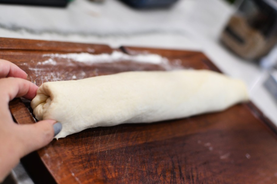 rolling dough to make cinnamon rolls 