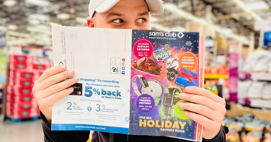 man holding up Sams Club holiday savings book