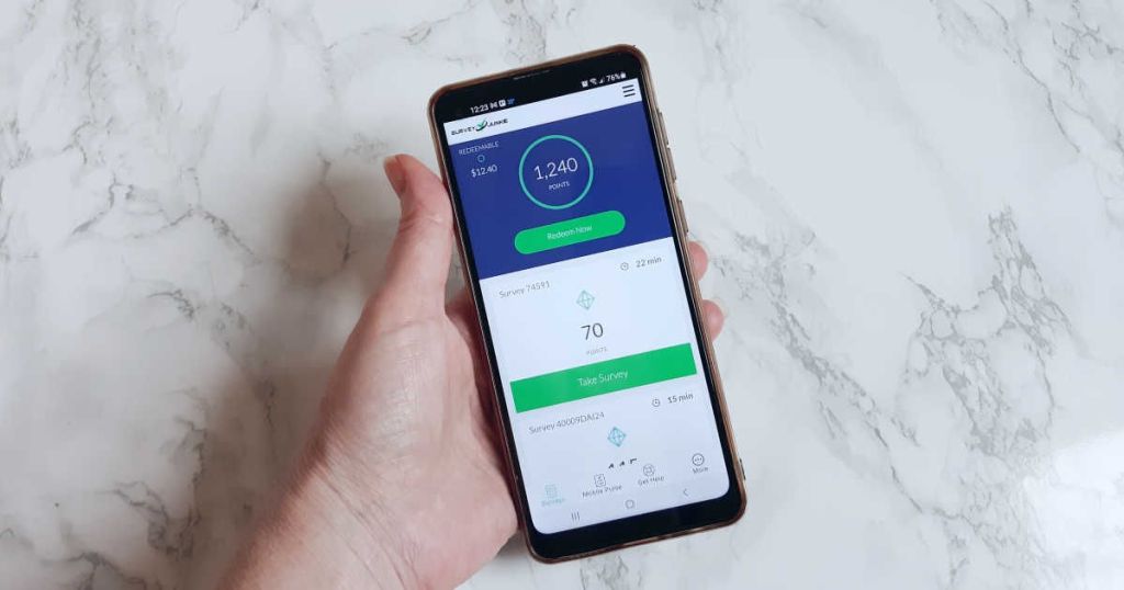 holding a phone with the Survey Junkie app open