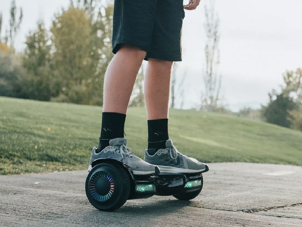 kids legs riding hoverboard on sidewalk