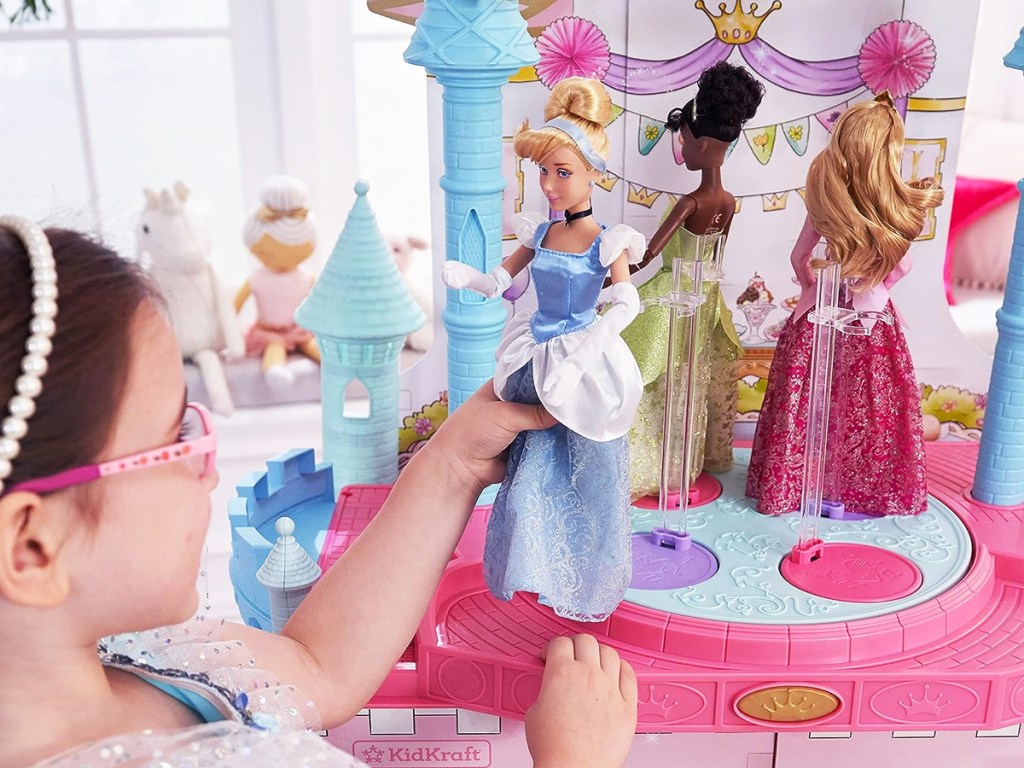 girl playing with dolls on top of dollhouse