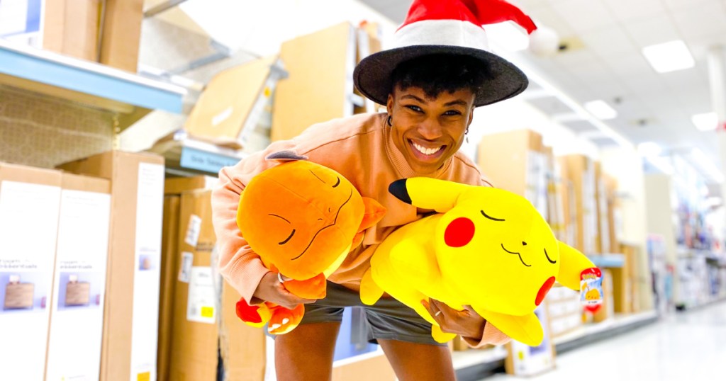 woman in Santa hat holding two Pokemon plush pillows in-store