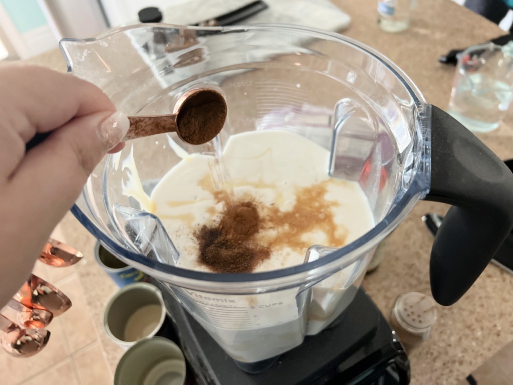 adding vanilla and spices to coquito