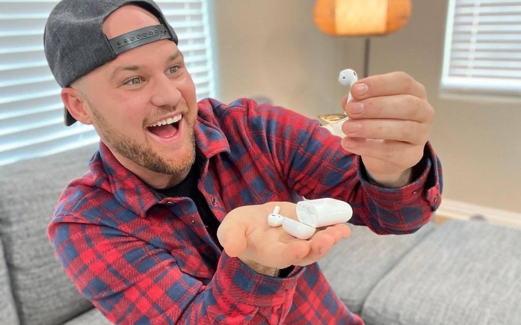 man holding a set of apple airpods in palm of hand looking excited