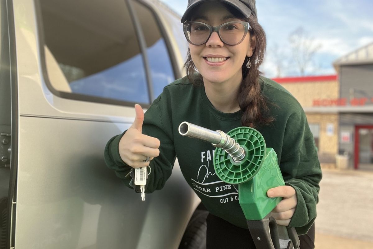 woman standing outside of car and holding a gas pump