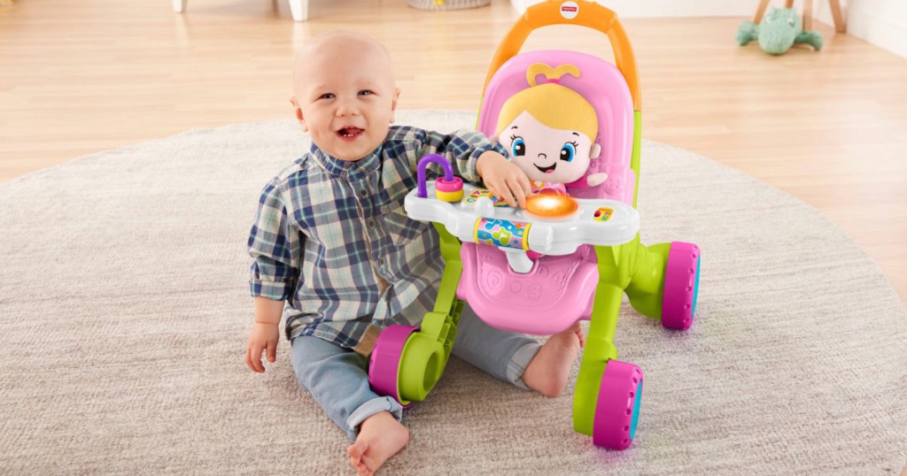 baby sitting next to a stroller walker toy with doll in it