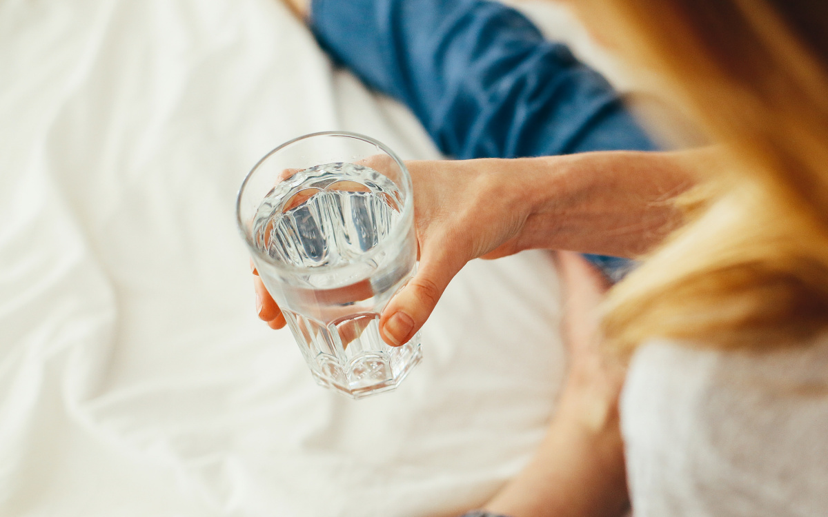 woman holding glass of water - how to get rid of a cold fast - cold remedies