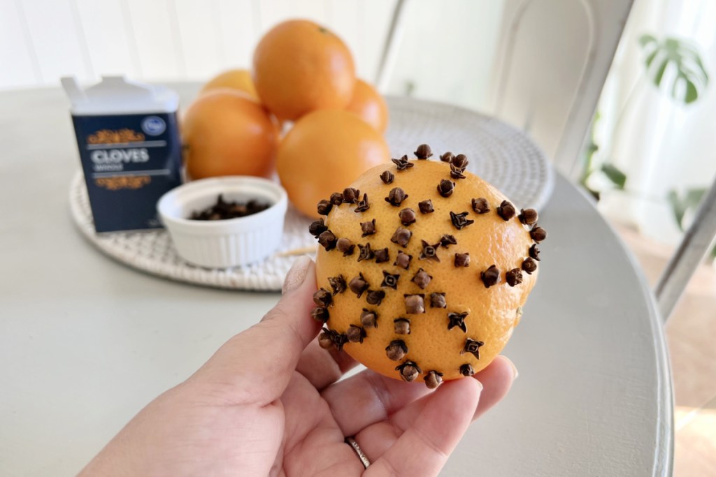 holding a pomander ball with cloves