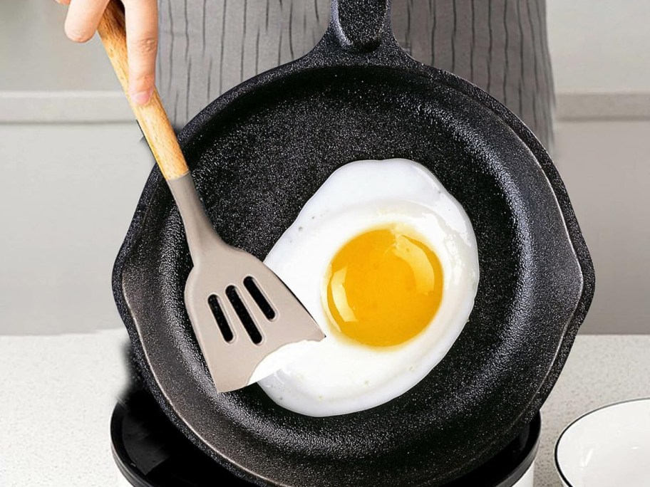 hands cooking egg on cast iron skillet 