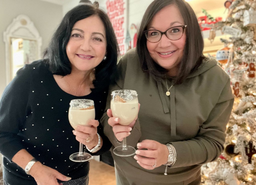 women holding coquito drinks