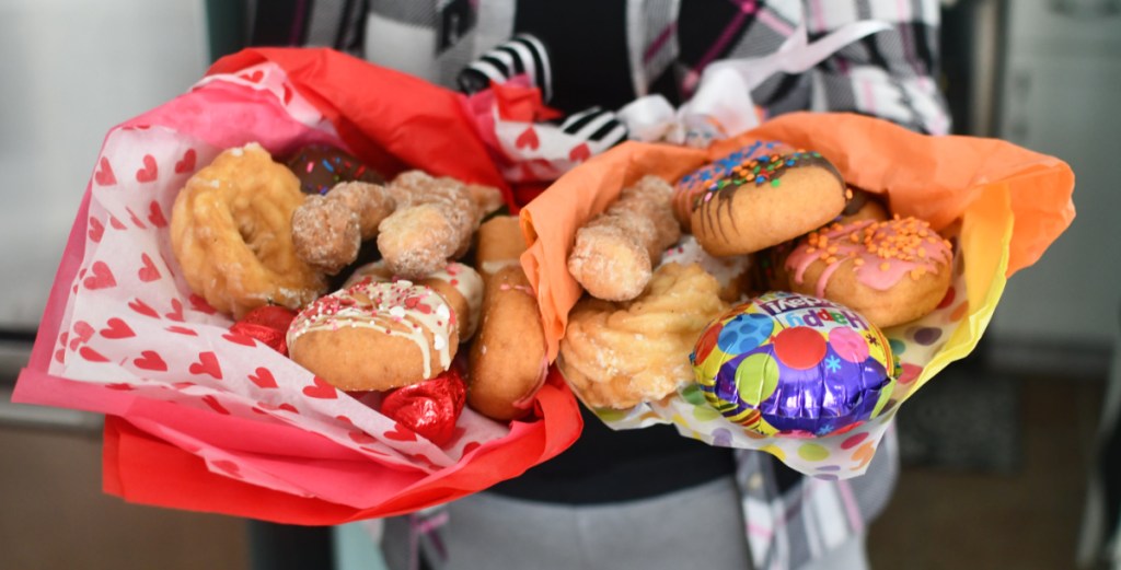 Woman holding up 2 DIY doughnut arrangements