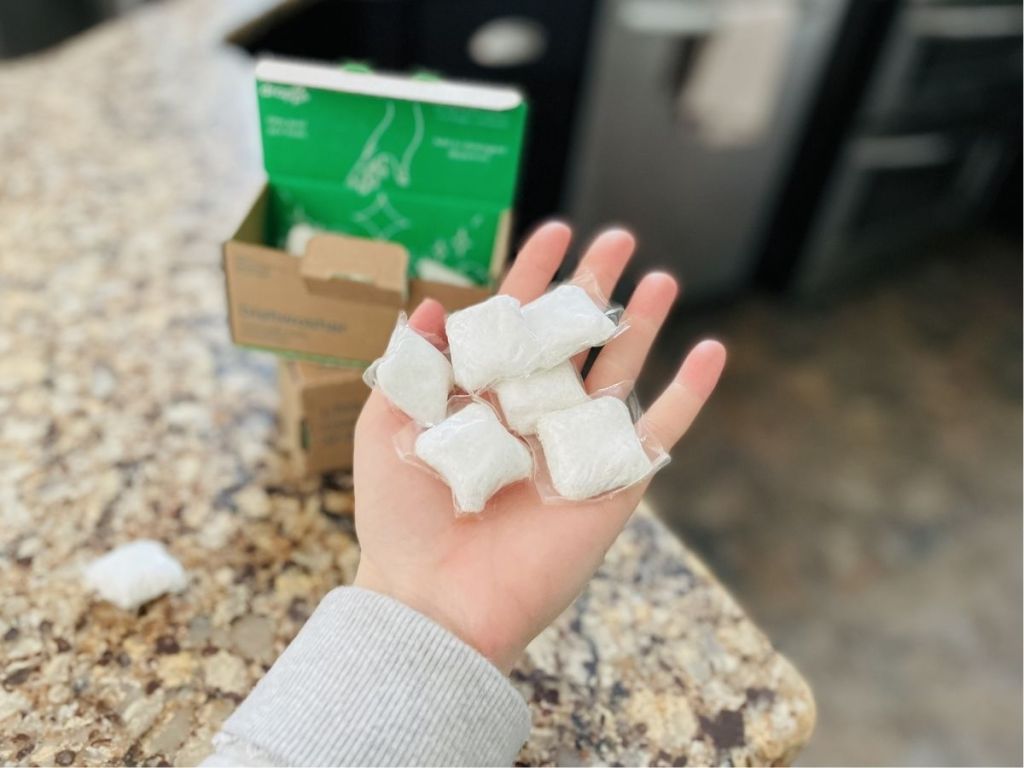 hand holding a bunch of white dishwasher pods over counter