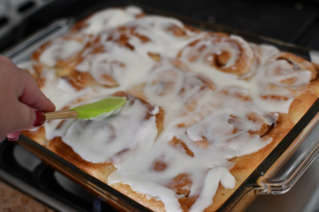 Spreading icing over cinnamon rolls