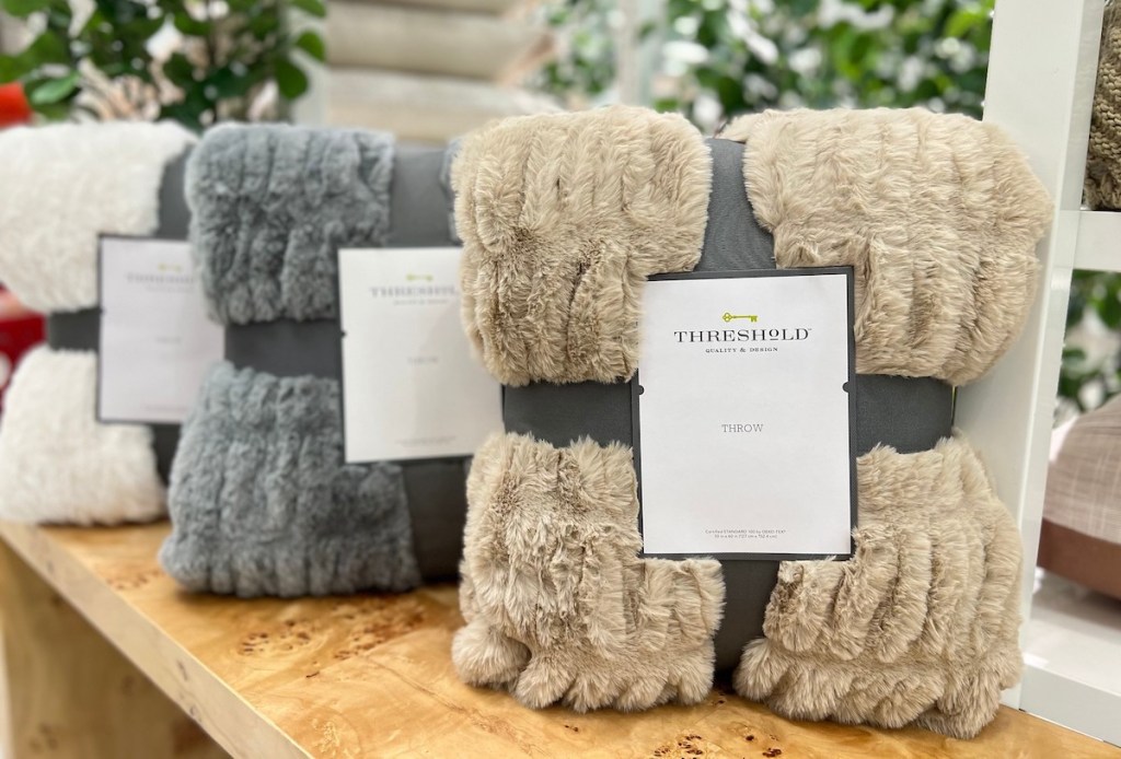 various faux fur throw blankets with threshold packaging on wood table