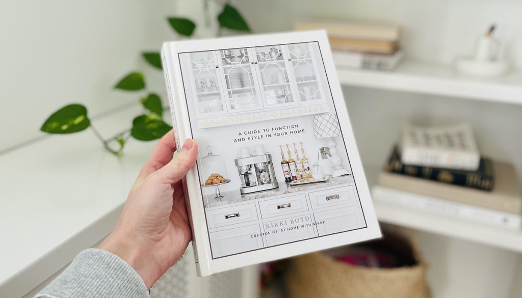 hand holding beautifully organized book in front of shelves