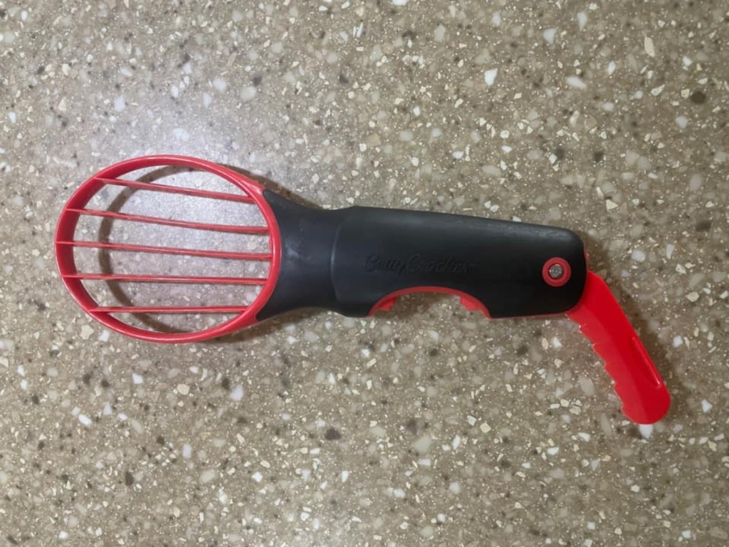 red and black avocado cutting tool on countertop