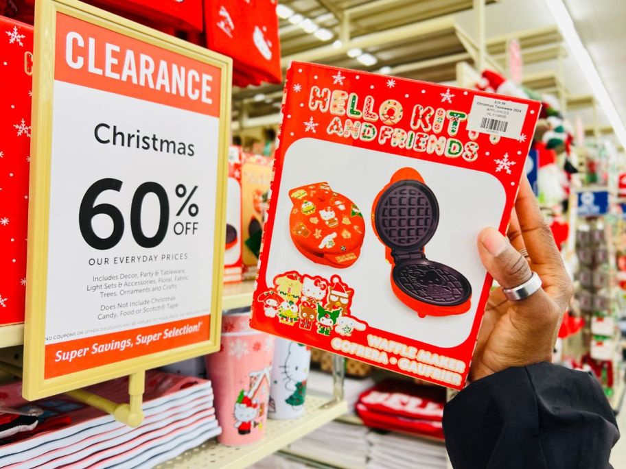 a womans hand holding a hello kitty holiday waffle maker