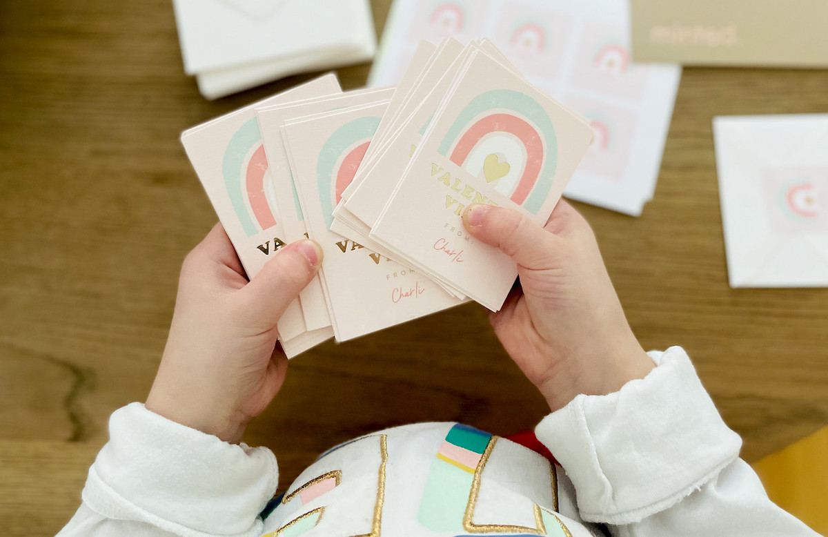 kids hands holding rainbow valentine vibes cards