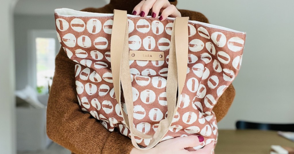 woman holding up a personalized tote bag in front of her body