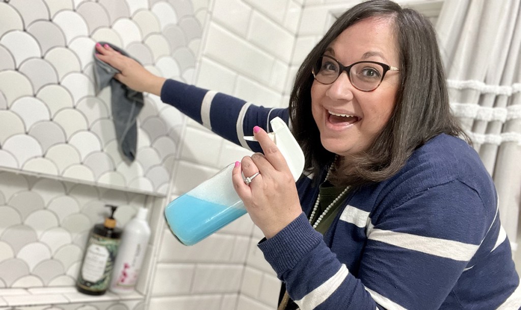 woman cleaning shower tile wall with diy shower cleaner