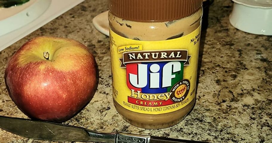 jar of peanut butter next to an apple